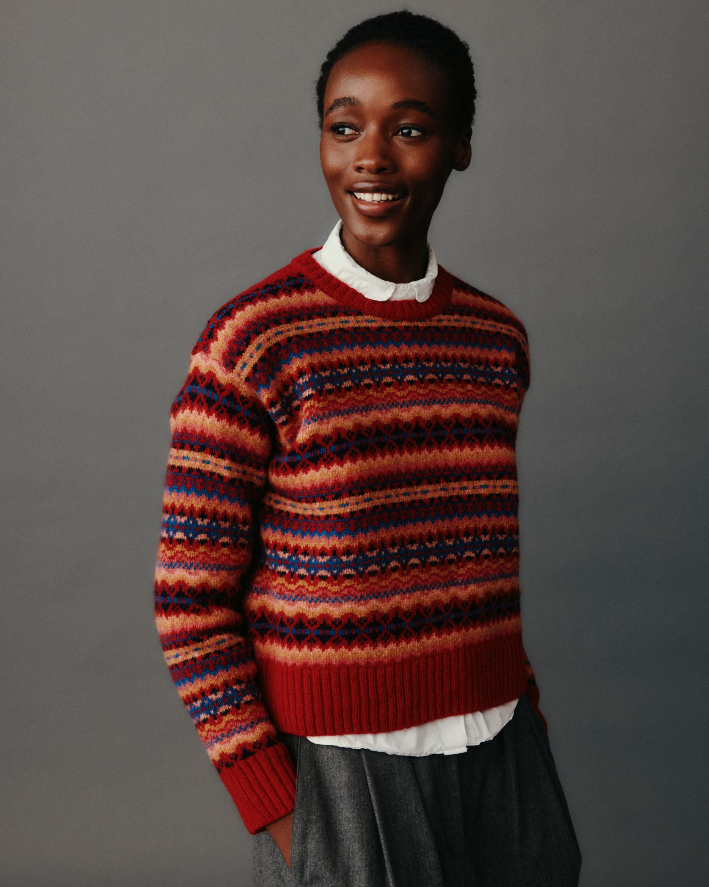 Person wearing a patterned sweater against a gray background