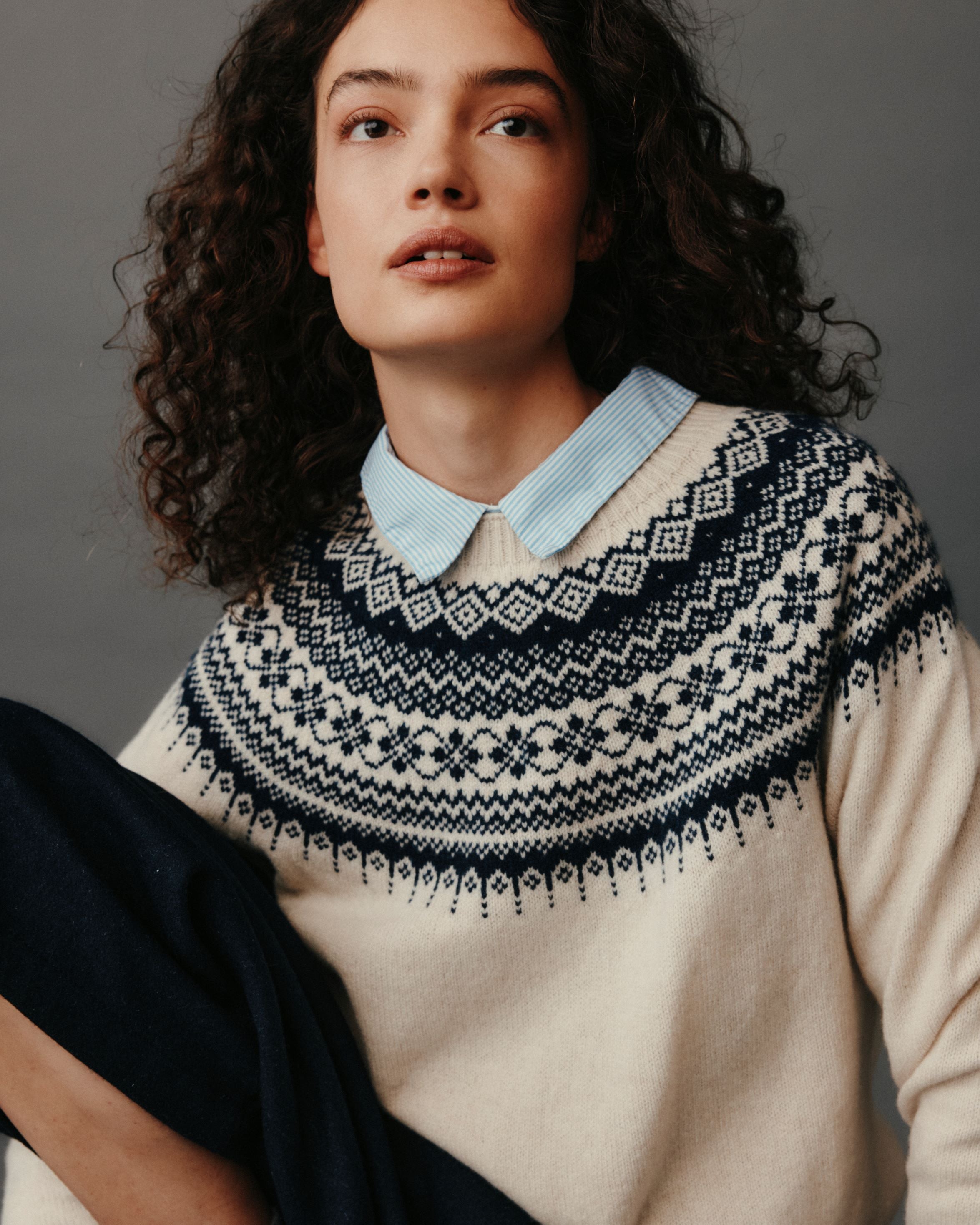Woman wearing a patterned sweater with a plain background