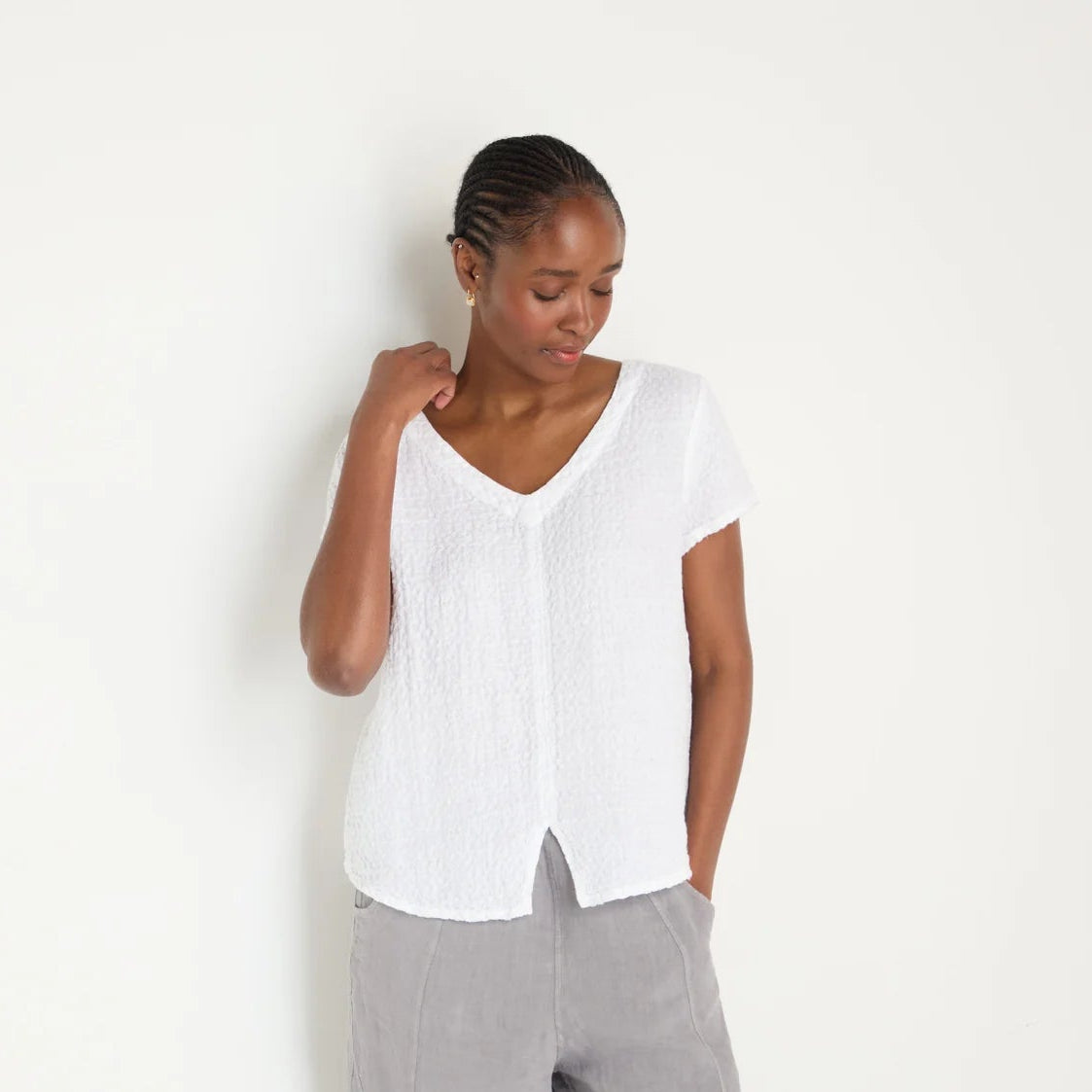 Woman wearing a white blouse and gray pants on a white background