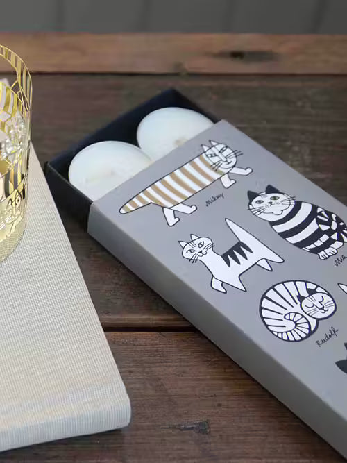 Candle packaging with cat illustrations on a wooden surface