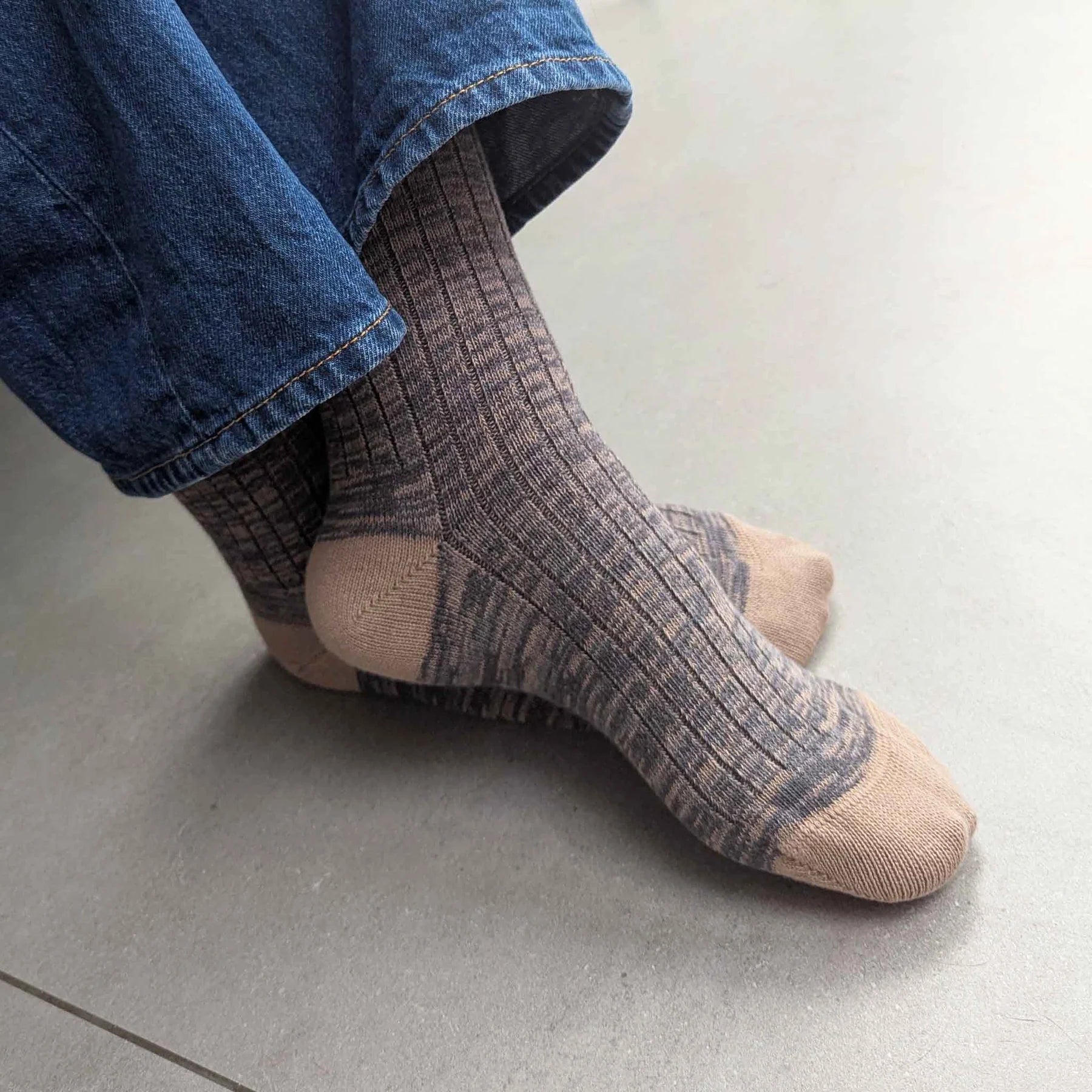 Person wearing plaid socks and blue jeans on a light gray floor.