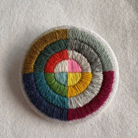 Circular patch with multicolored concentric circles on a light gray background