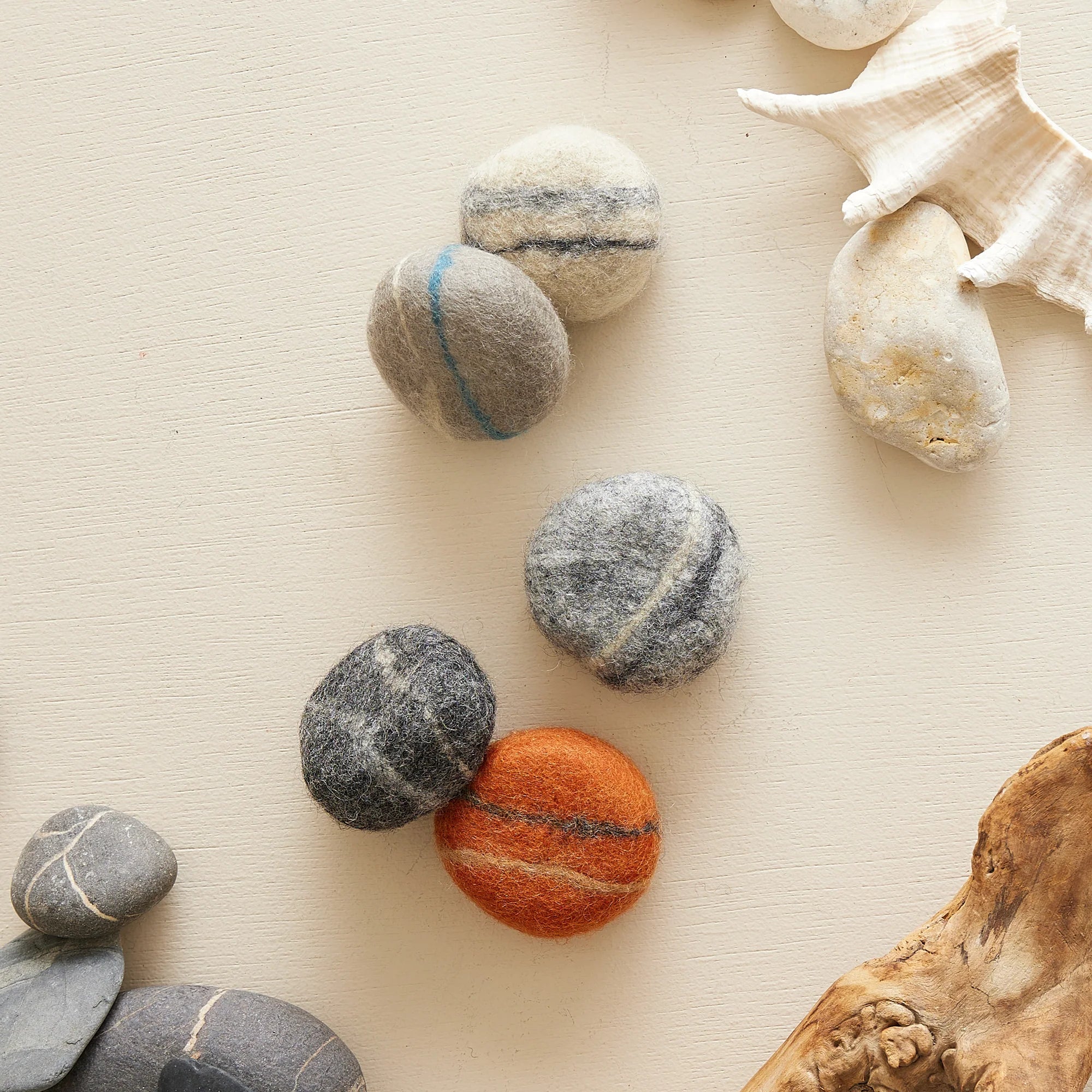 Five felted wool stones; gray, orange, and dark gray with lighter veining.
