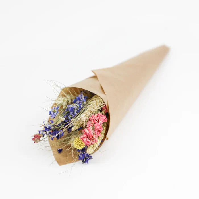 Dried flower bouquet in brown paper cone.  Includes blue, pink, and yellow flowers with wheat stalks.