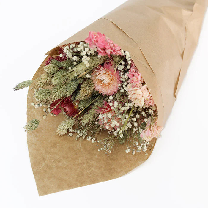 Dried flower bouquet in kraft paper wrapping.  Includes pink, peach, and green blooms; various textures and sizes.