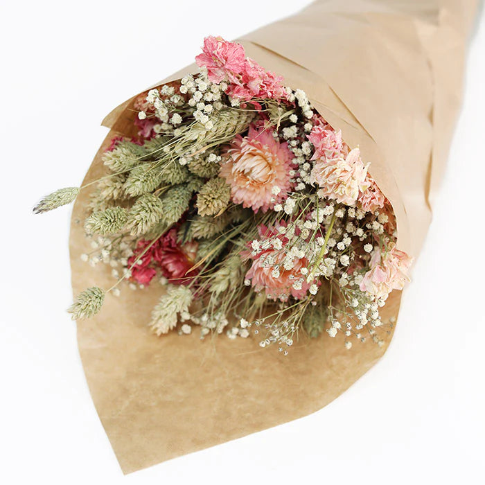 Dried flower bouquet in kraft paper wrapping.  Includes pink and peach flowers, and various dried grasses.