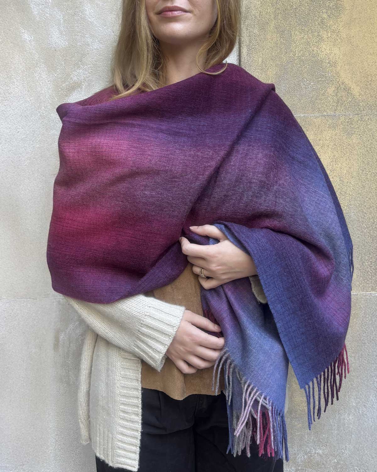 Person wearing a purple and blue gradient shawl against a neutral background