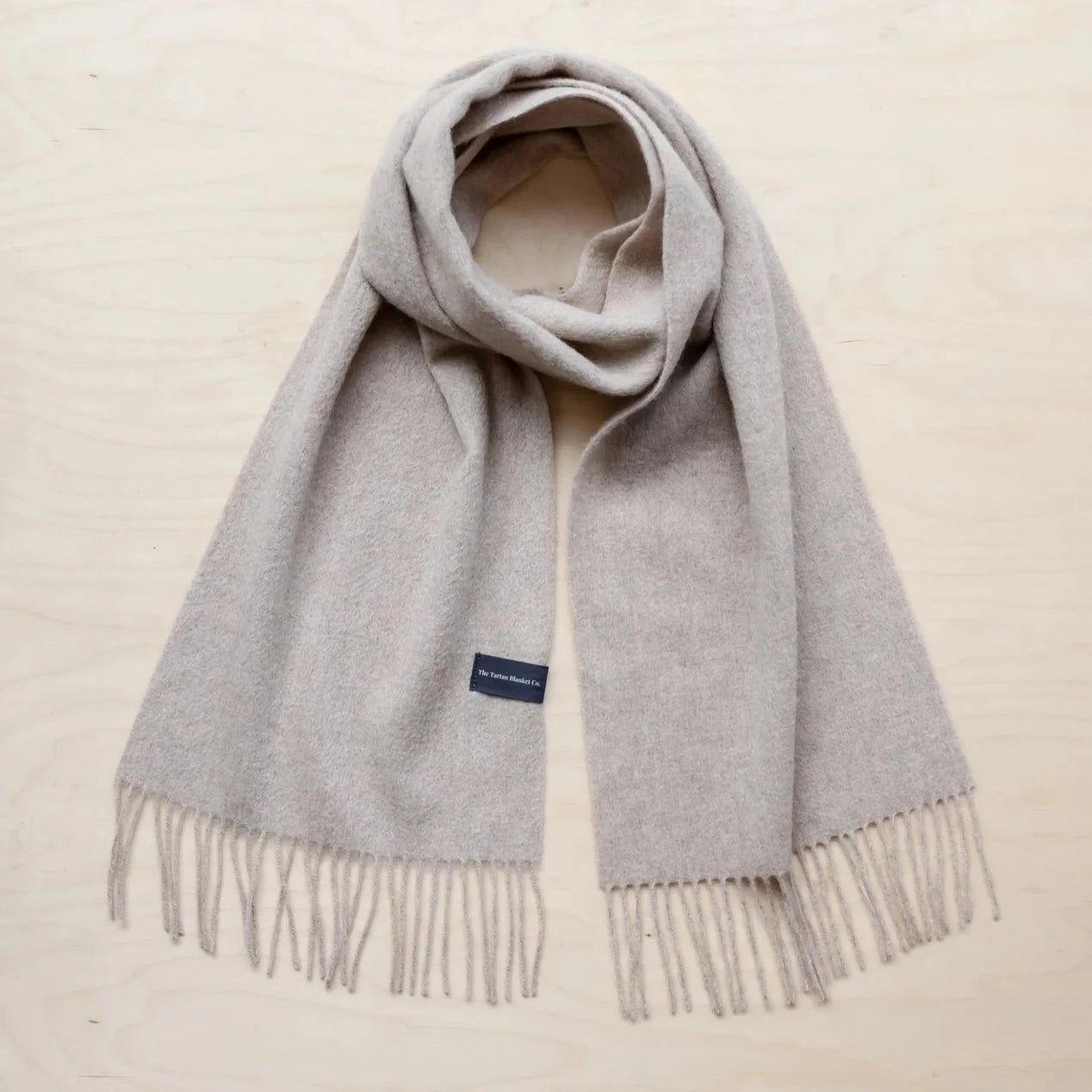 Light beige wool scarf with fringe detailing.