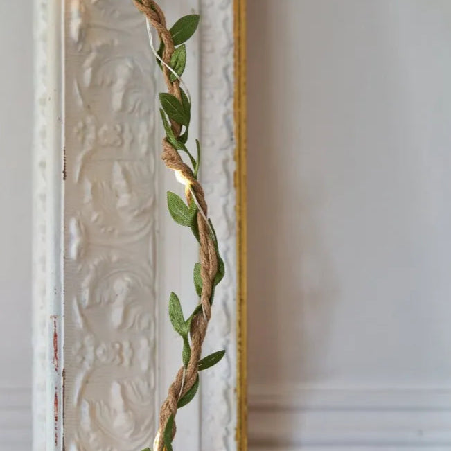 LED string lights wrapped in jute rope and adorned with artificial leaves.
