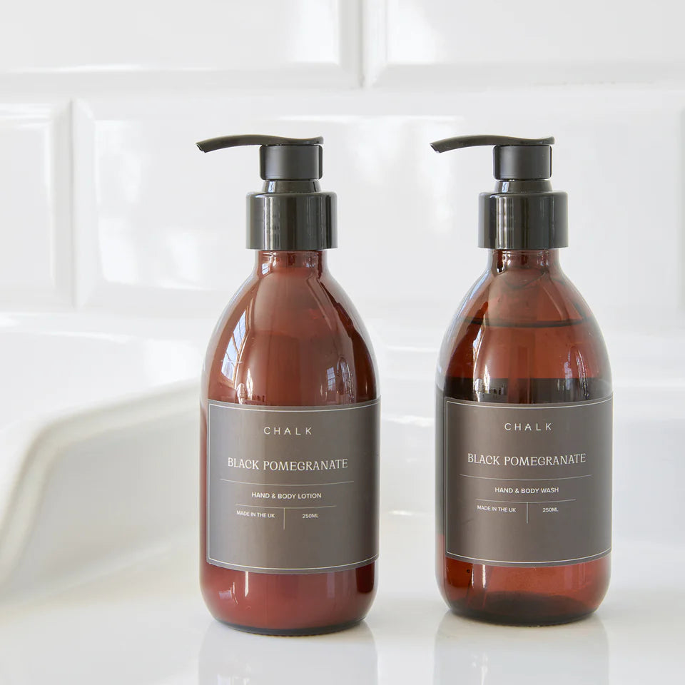 Two bottles of Chalk Black Pomegranate hand and body products on a white surface.