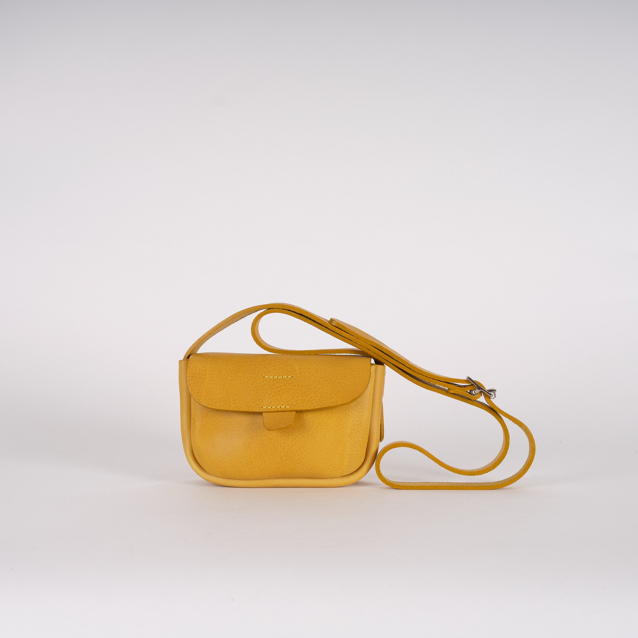 Mustard yellow leather crossbody bag with a flap closure and adjustable strap.