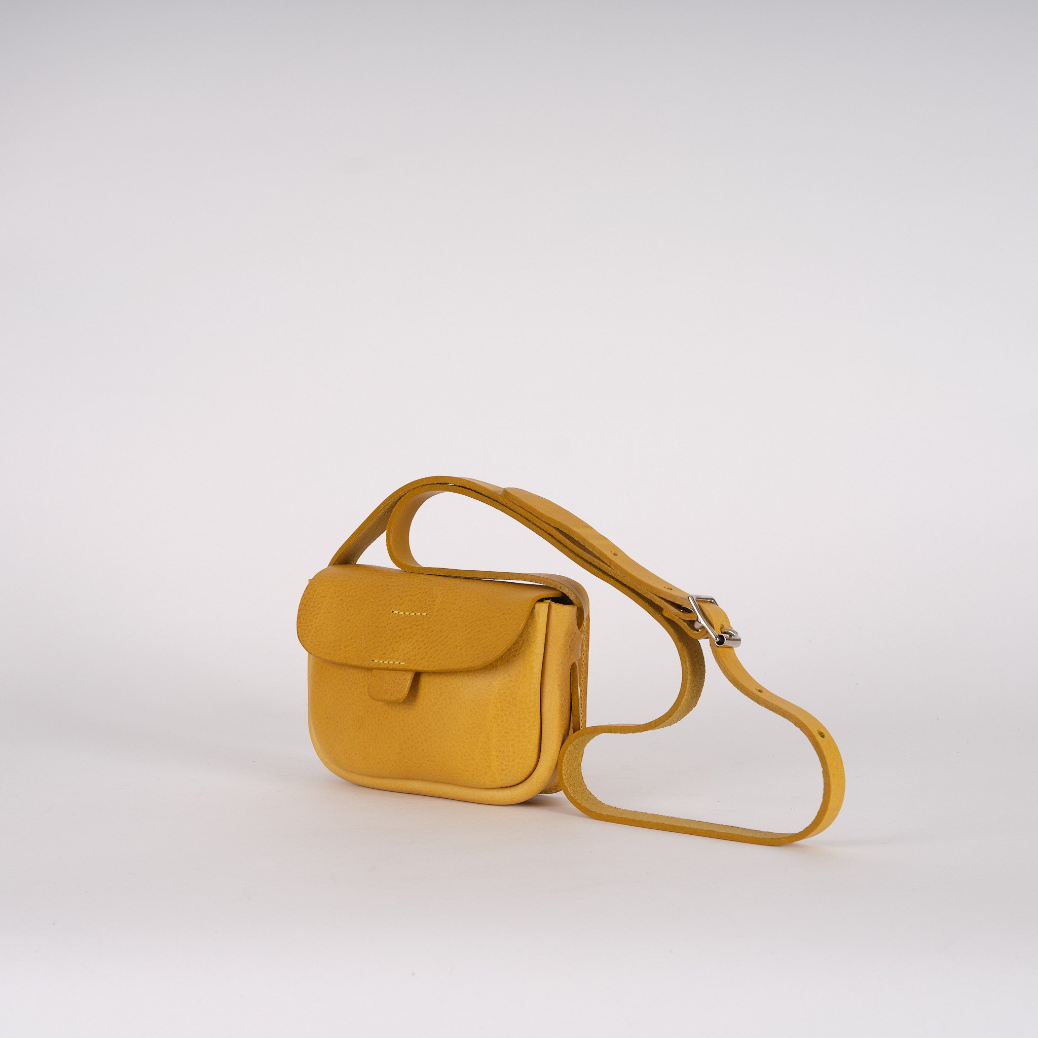Mustard yellow leather crossbody bag with a flap closure and adjustable strap.