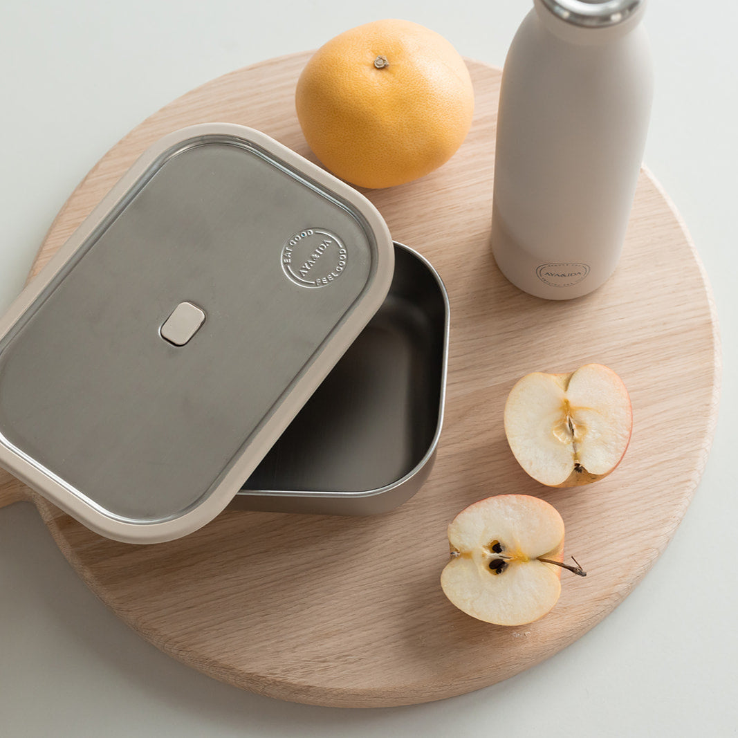 Stainless steel rectangular bento box with lid, slightly ajar, showing interior.  Ayama brand logo visible on lid.