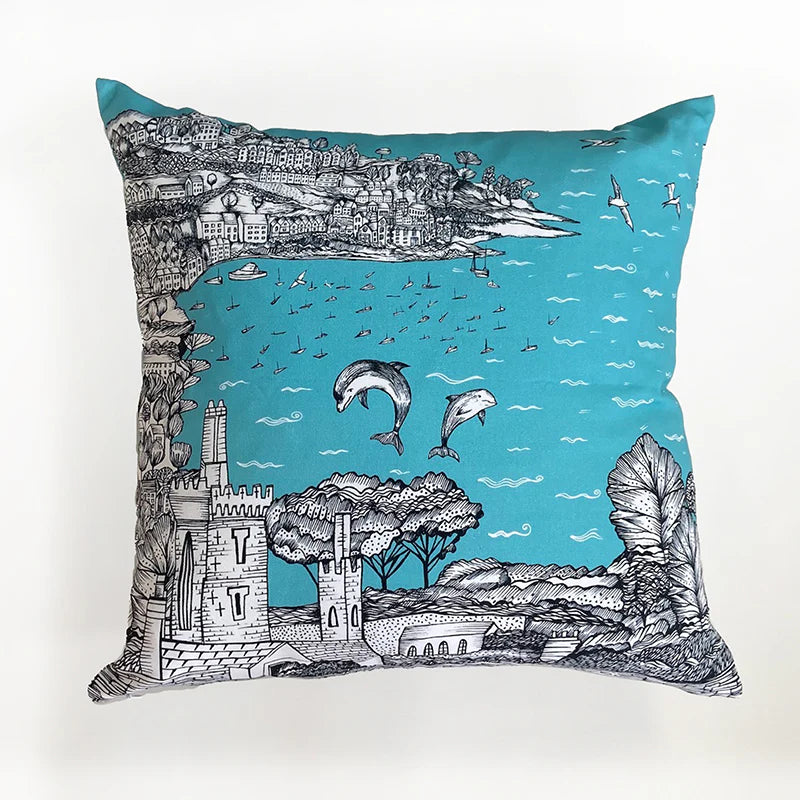 Teal cushion featuring a black and white illustration of a coastal scene with dolphins jumping, boats, and buildings.