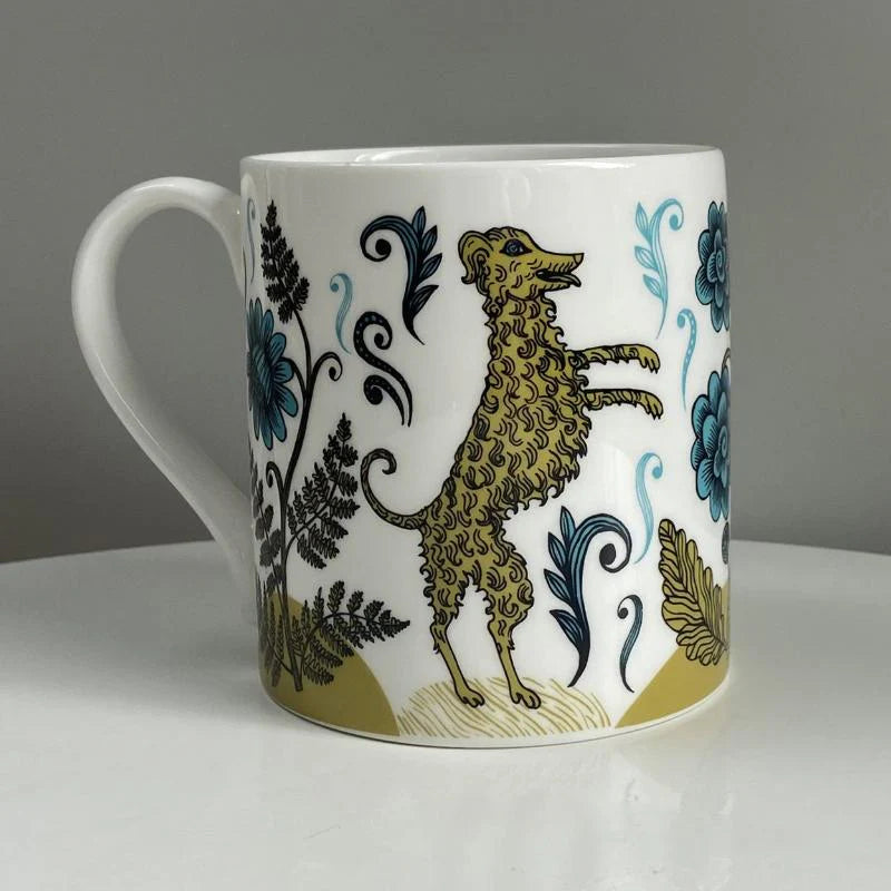 White mug with a whimsical illustration of a yellow dog amongst teal flowers and ferns.