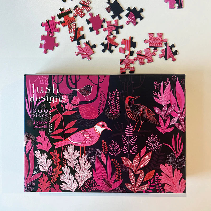 Lush Design puzzle box with bird and floral design, surrounded by scattered puzzle pieces.