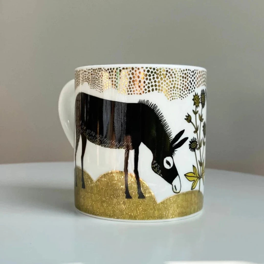 Porcelain mug featuring a black donkey illustration, gold accents, and green botanical details.