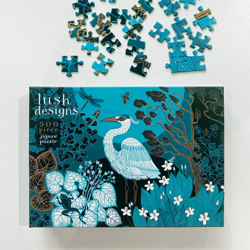 500-piece Lush Designs jigsaw puzzle featuring a teal and gold heron amidst stylized foliage and insects.