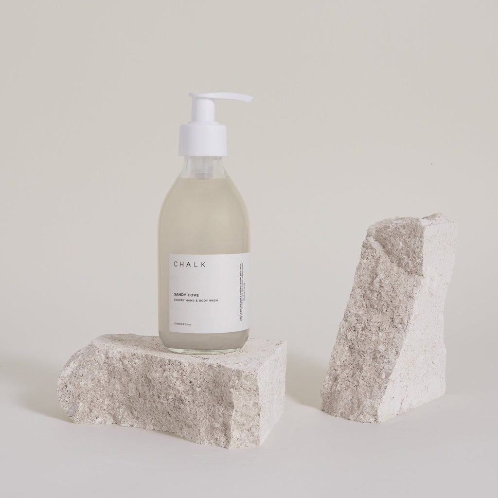 Chalk UK hand wash "Sandy Cove" in a clear bottle, placed on textured light stone, with a neutral backdrop.
