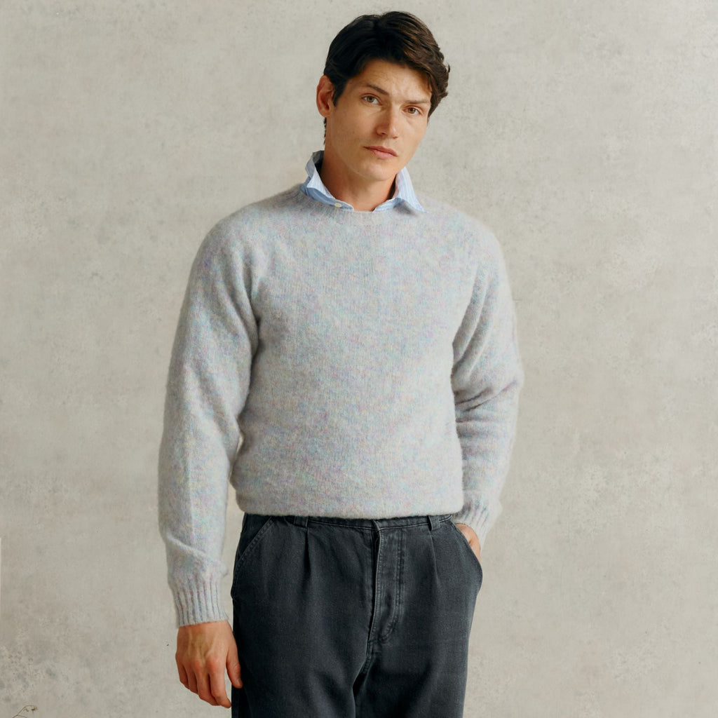 a male model with one hands in the pocket of a pair of grey corduroy trousers, wearing a blue collared shirt and a Harley of Scotland Men's Jumper - Ugie Pearl