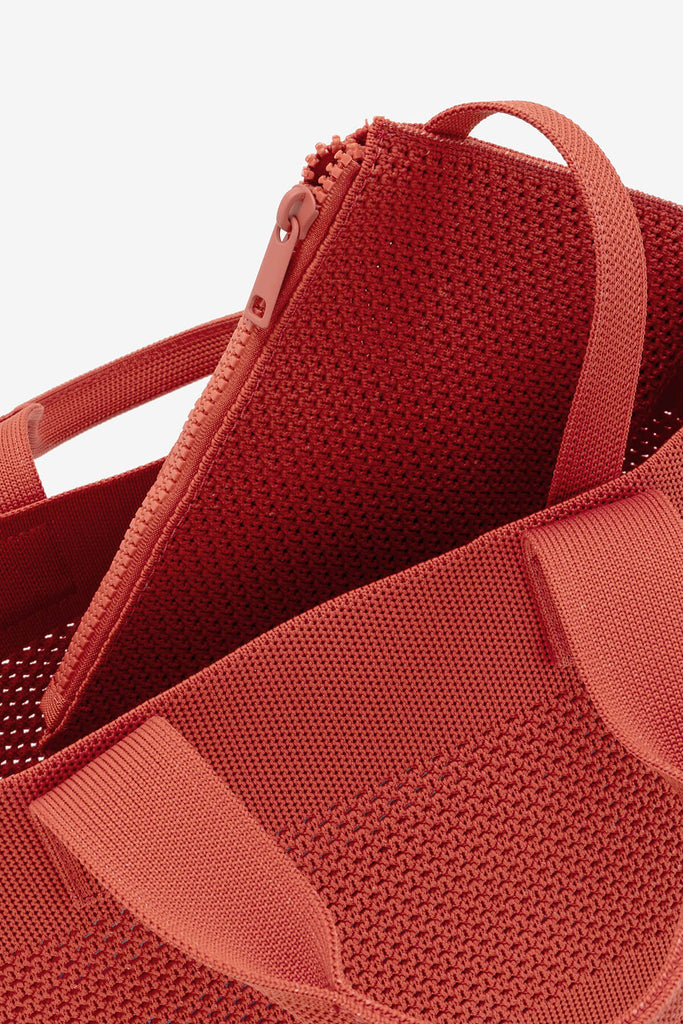 Red Ecoalf bag with textured fabric and a zippered inner pocket, featuring matching handles.