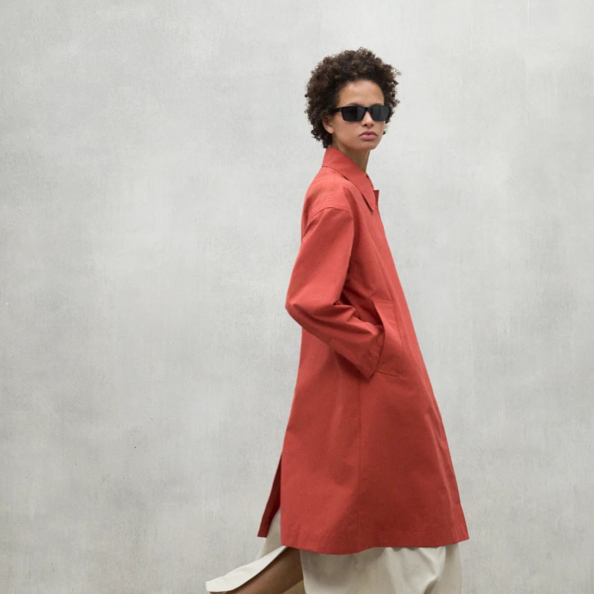 Burnt orange, knee-length collared coat with pockets.