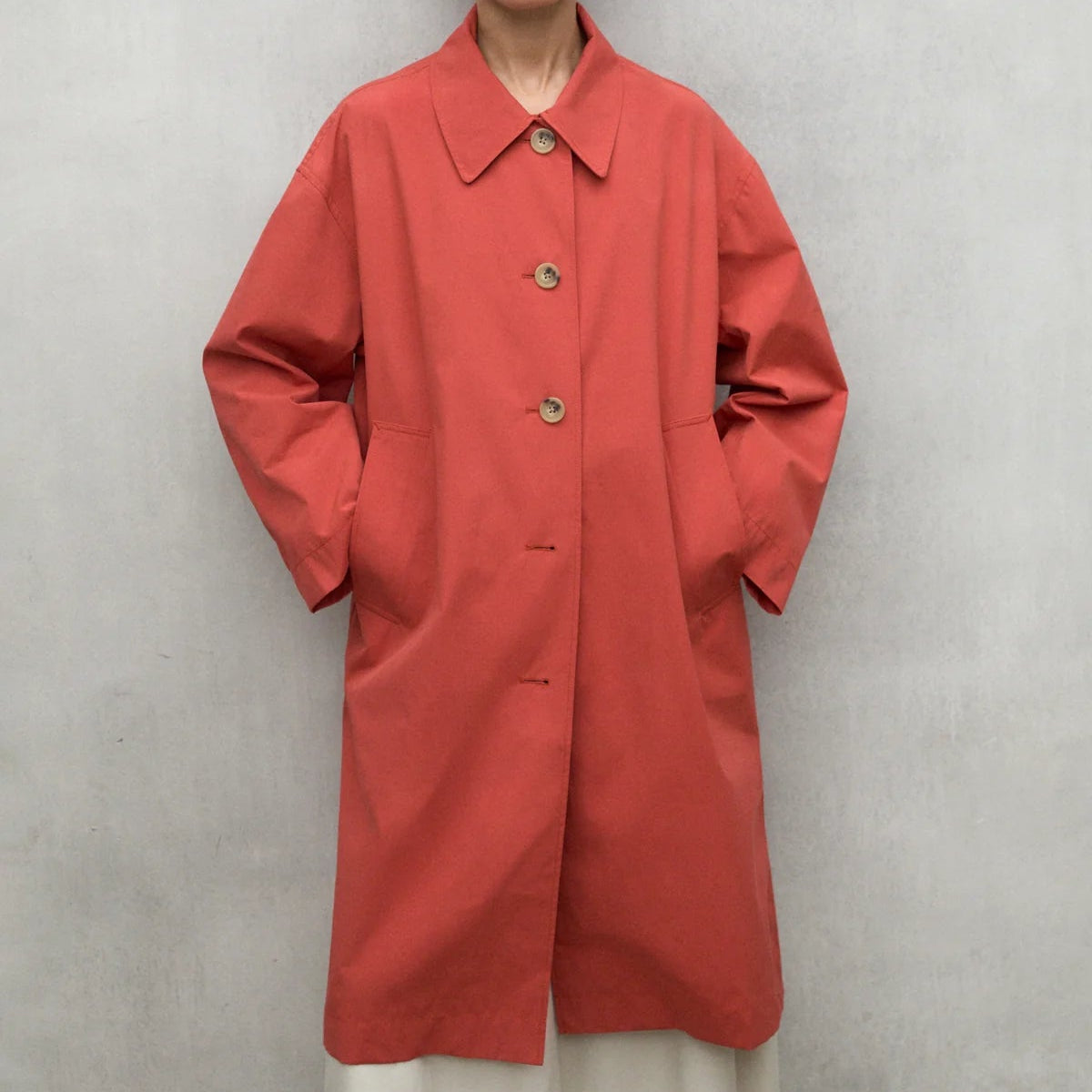 Coral-colored button-front coat with patch pockets and a collared neckline.