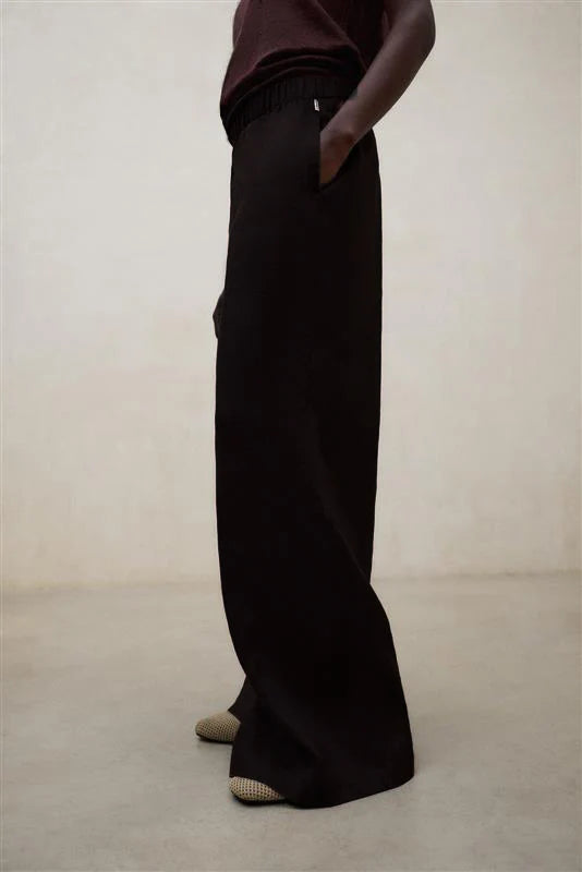 Person wearing black wide-leg pants on a plain background