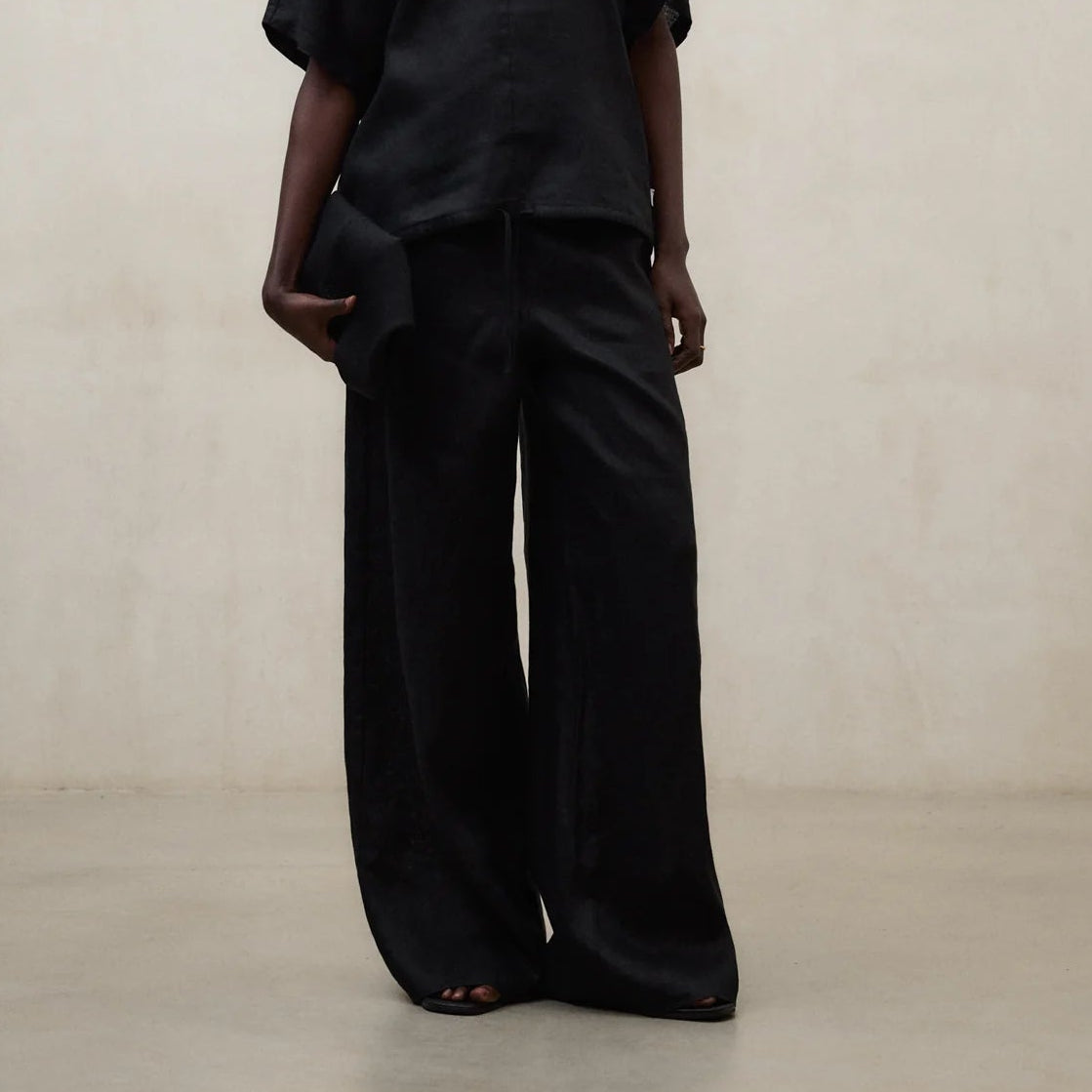 Person wearing a black outfit with a yellow scarf against a neutral background