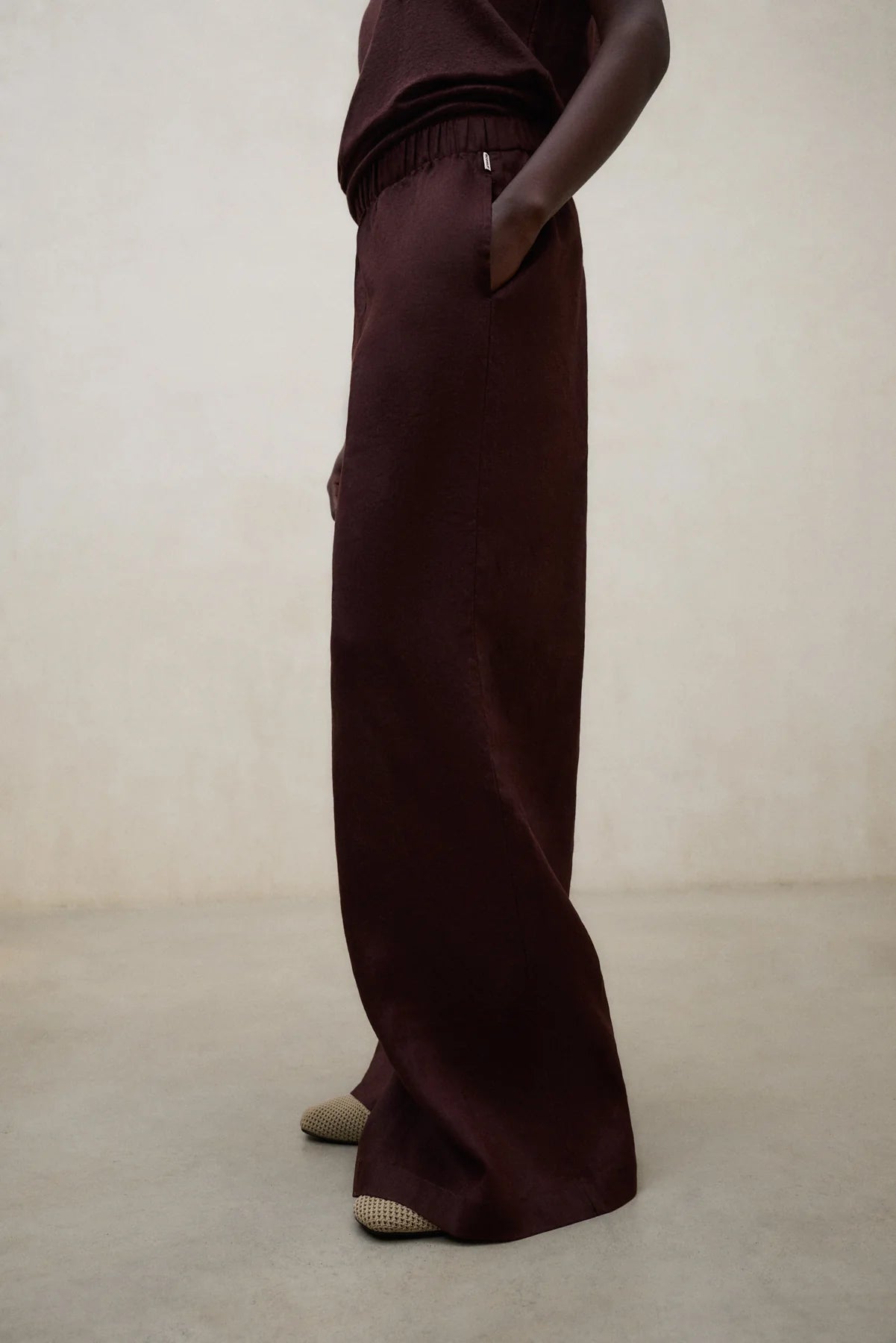 Person wearing dark brown pants on a plain background