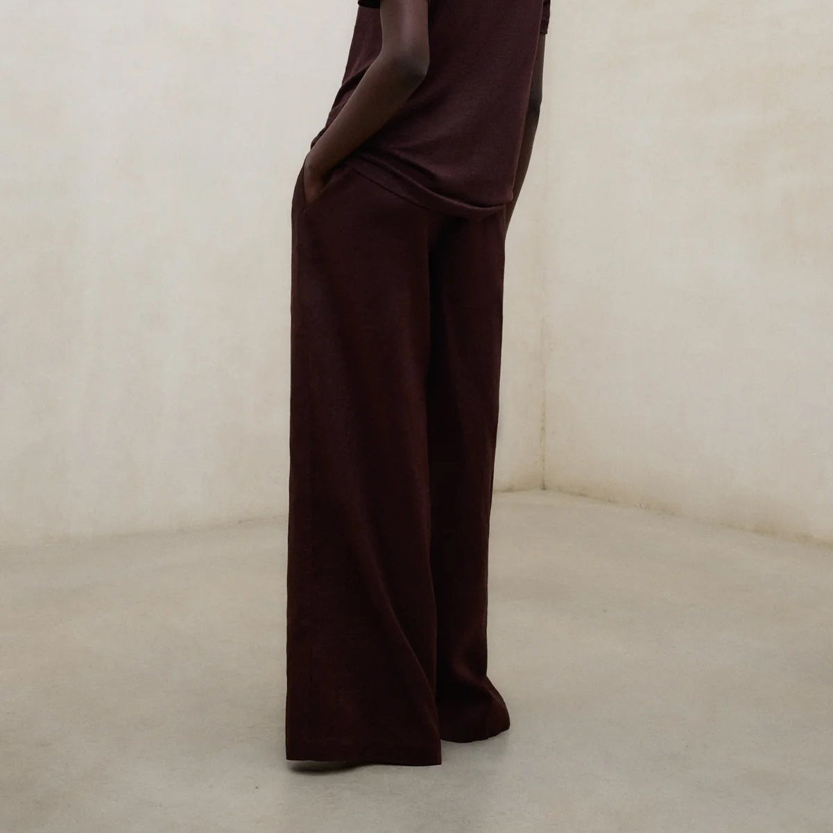 Person wearing a brown outfit standing against a plain background