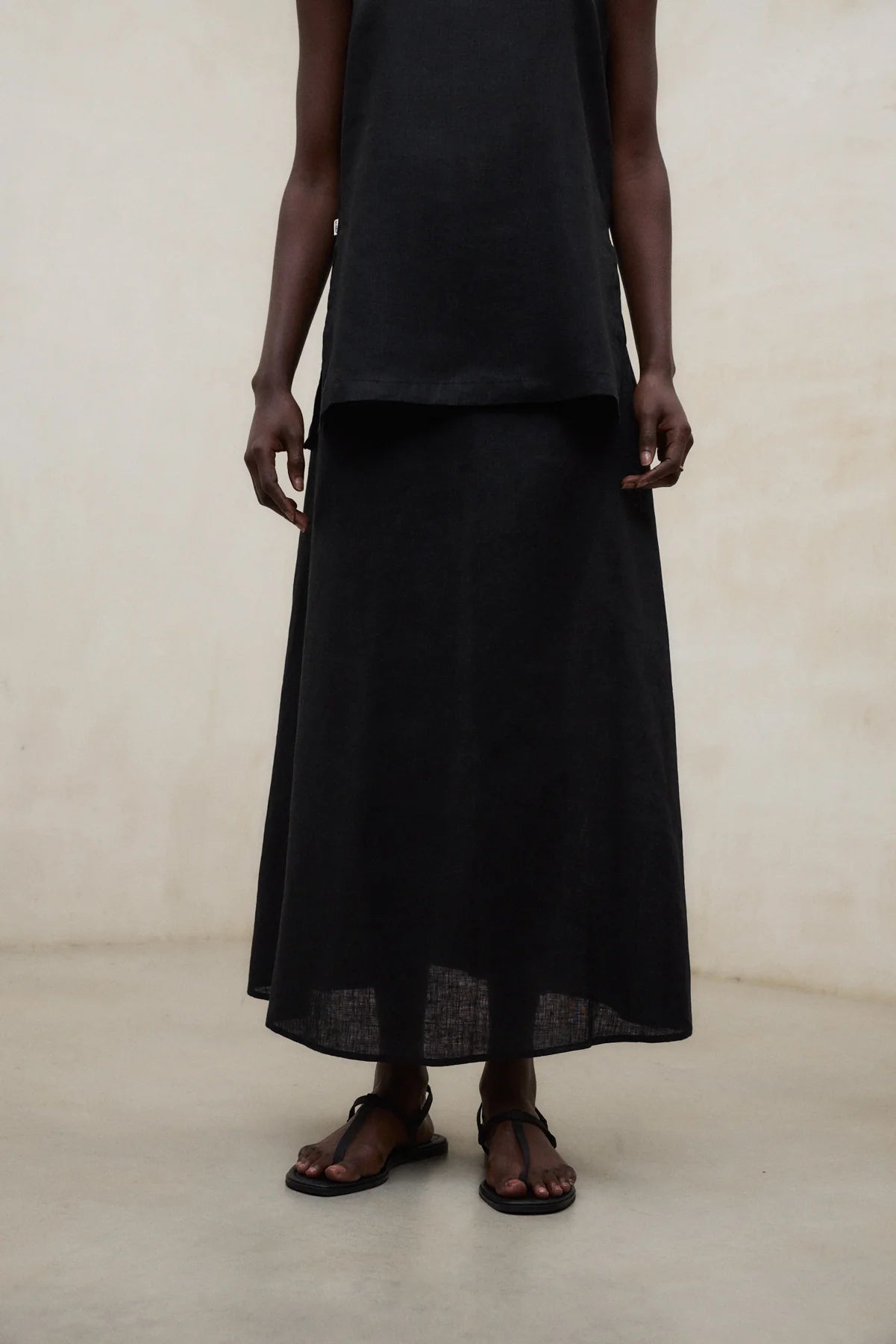 Person wearing a black outfit against a neutral background