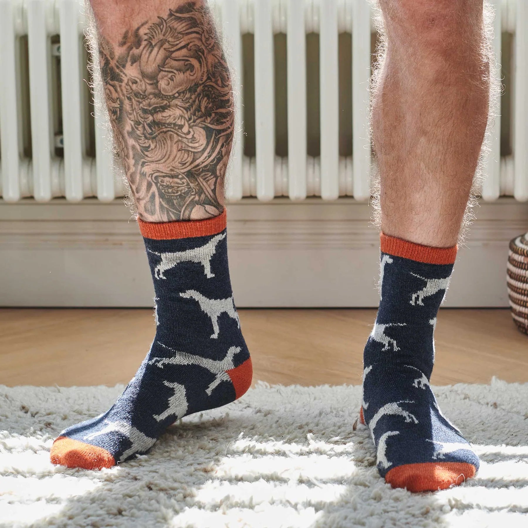 Person wearing navy socks with dog patterns and orange toes on a wooden floor.