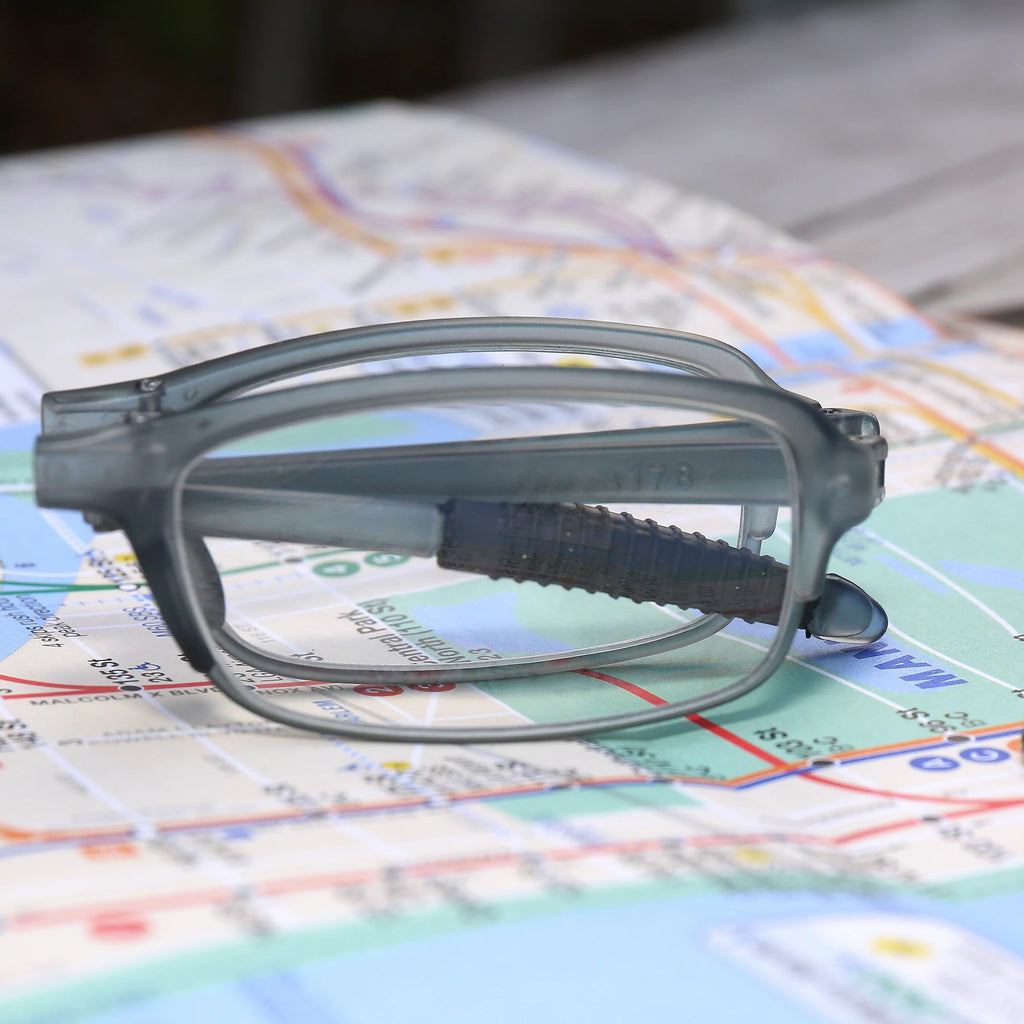 Gray folding reading glasses resting on a map.