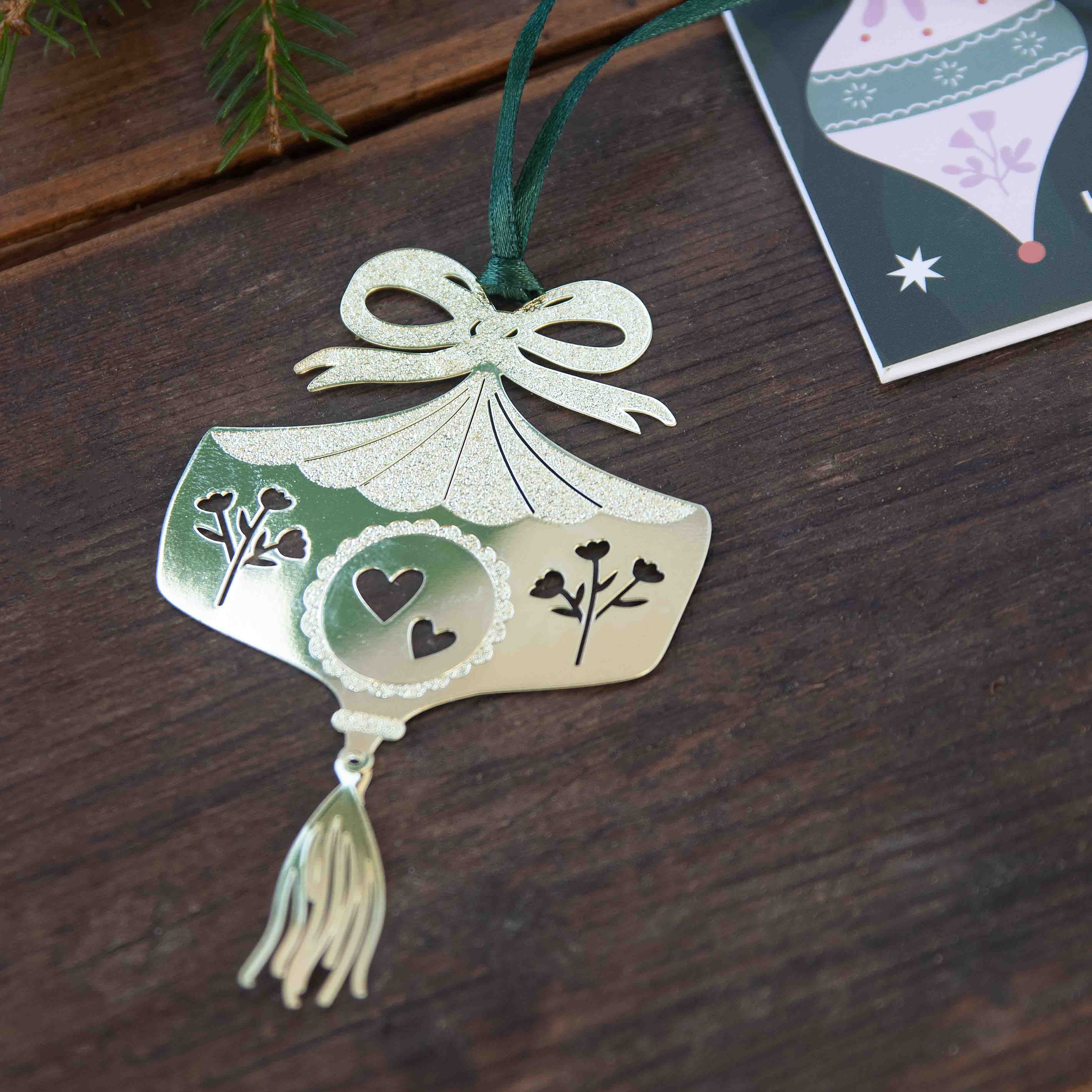 Decorative ornament with tassel on a wooden surface next to a Christmas card.