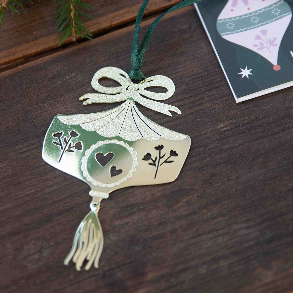 Decorative ornament with tassel on a wooden surface next to a Christmas card.