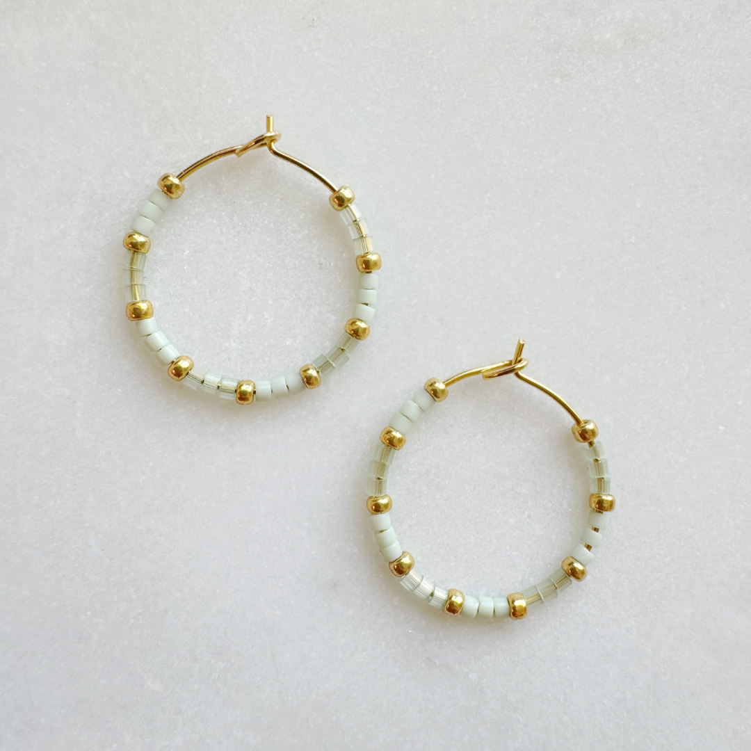 A pair of pale green mini hoop earrings with gold-plated and nickel-free accents, displayed against a light background.