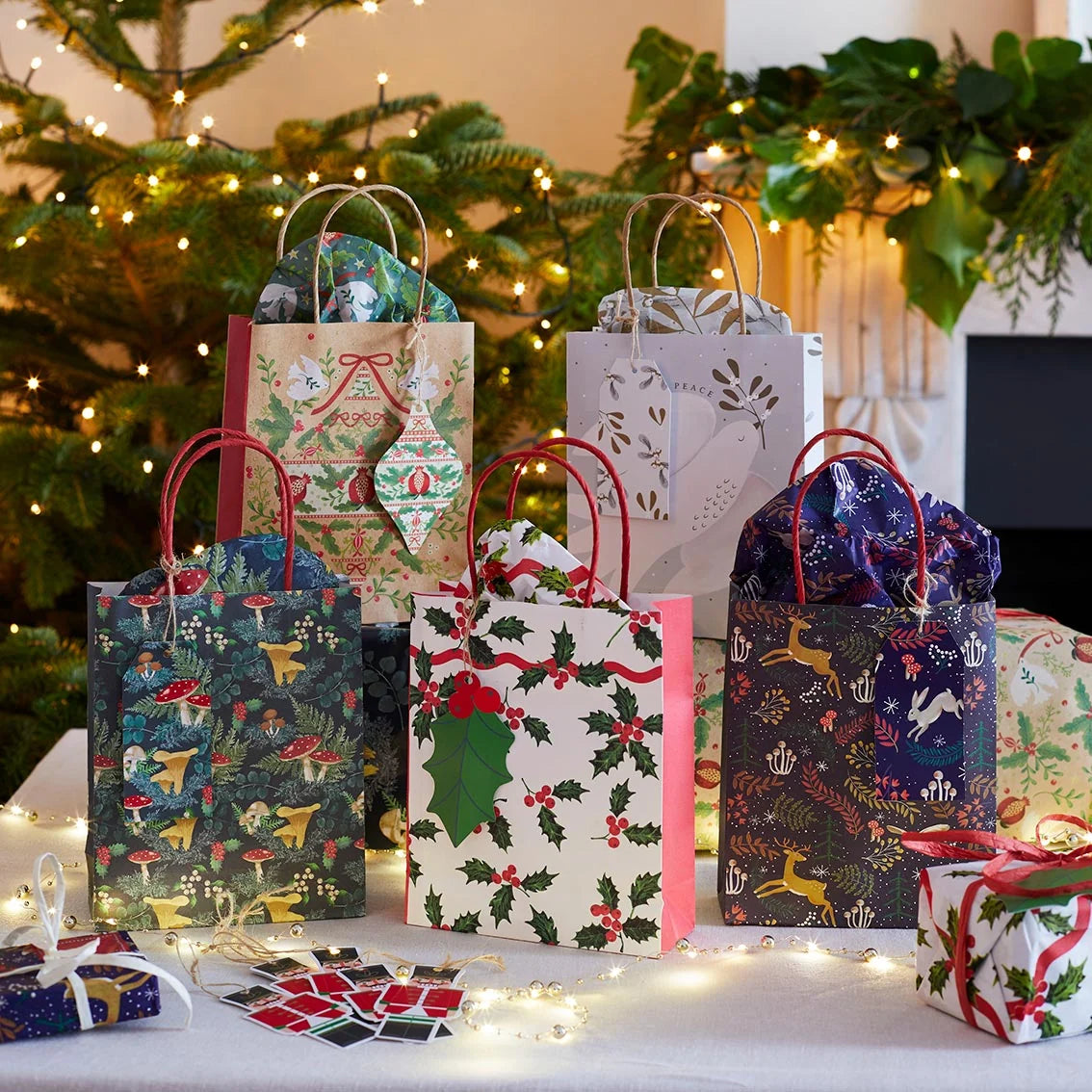Decorative Christmas gift bags with holly and reindeer designs on a festive background.