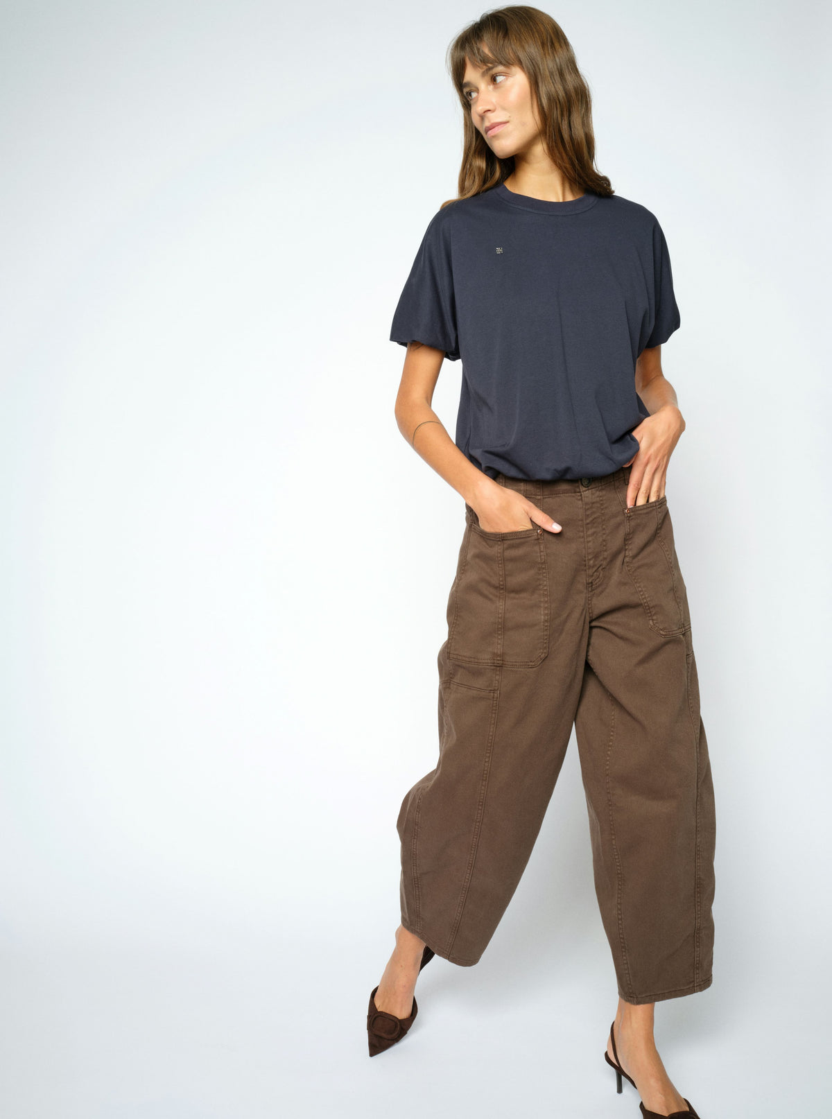 Woman wearing a navy t-shirt and brown wide-leg pants on a white background