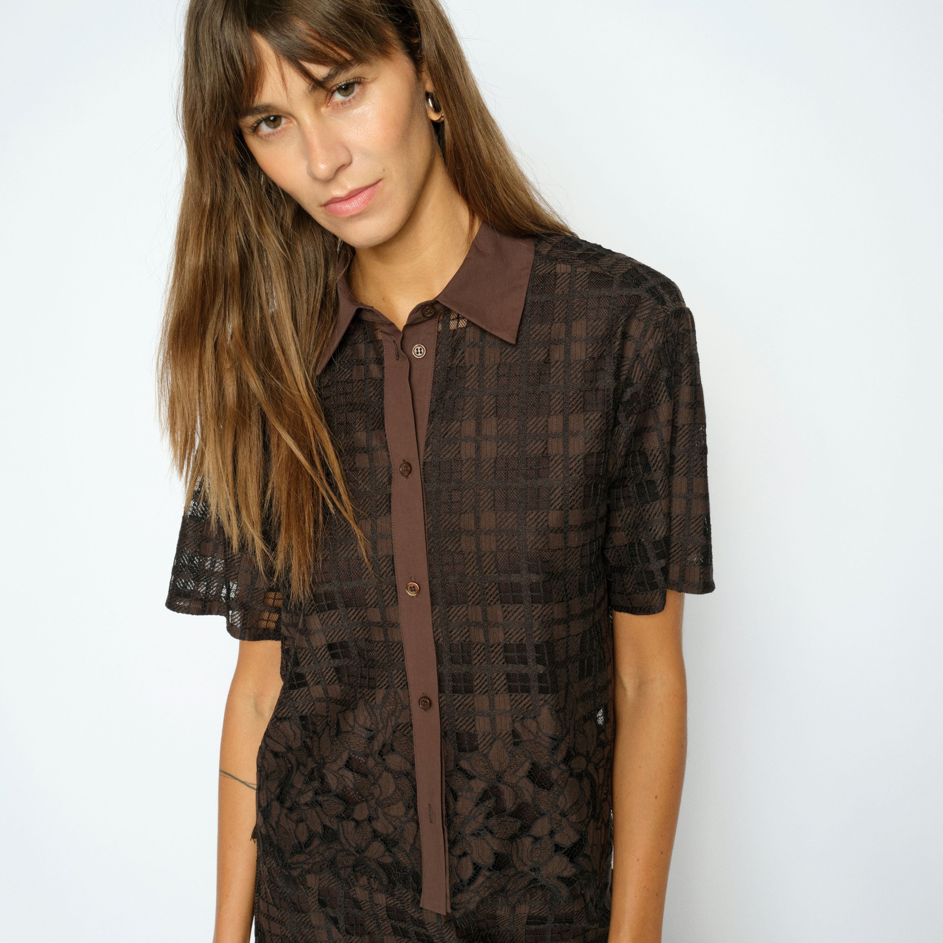 Woman wearing a brown checkered dress against a white background