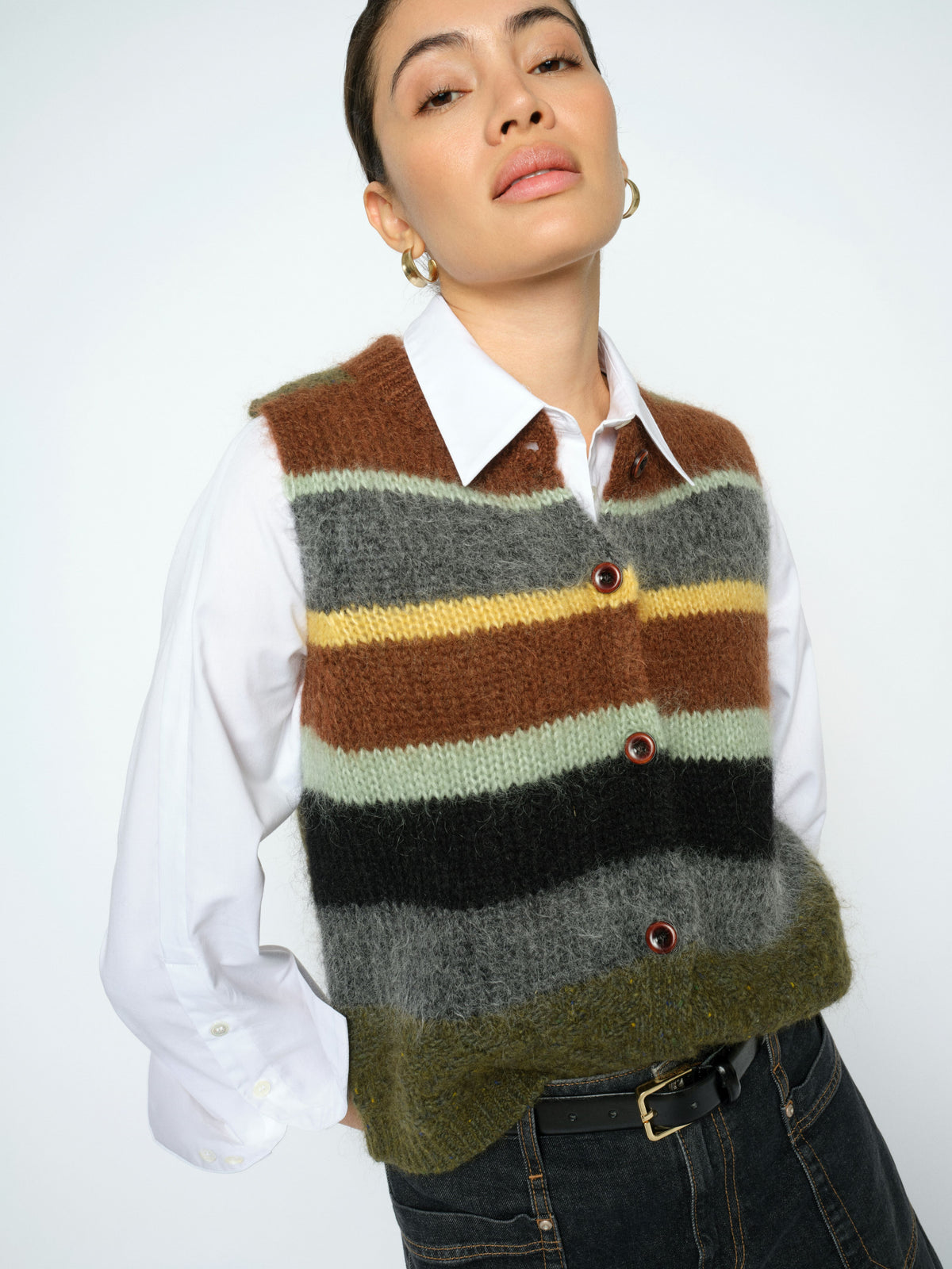 Person wearing a striped sweater vest over a white shirt on a plain background