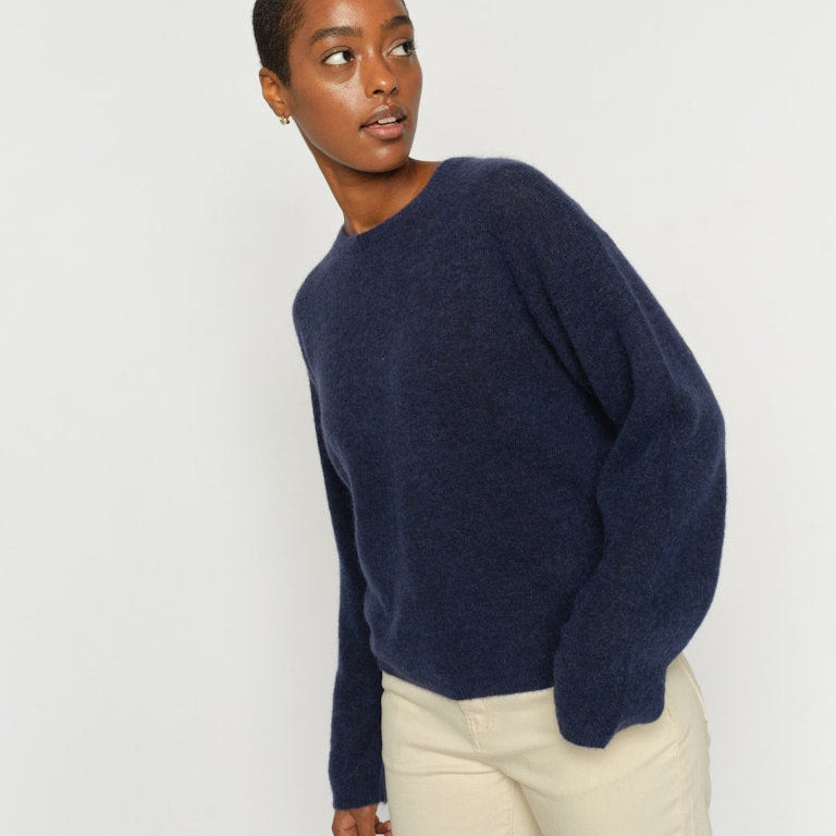 Person wearing a navy sweater against a white background