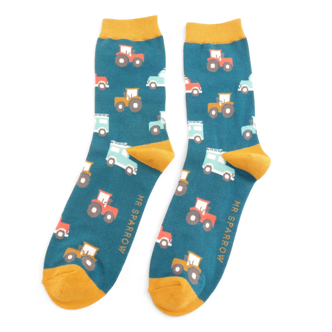 Pair of teal socks with a repeating pattern of colorful tractors and cars.  Mustard yellow cuffs.