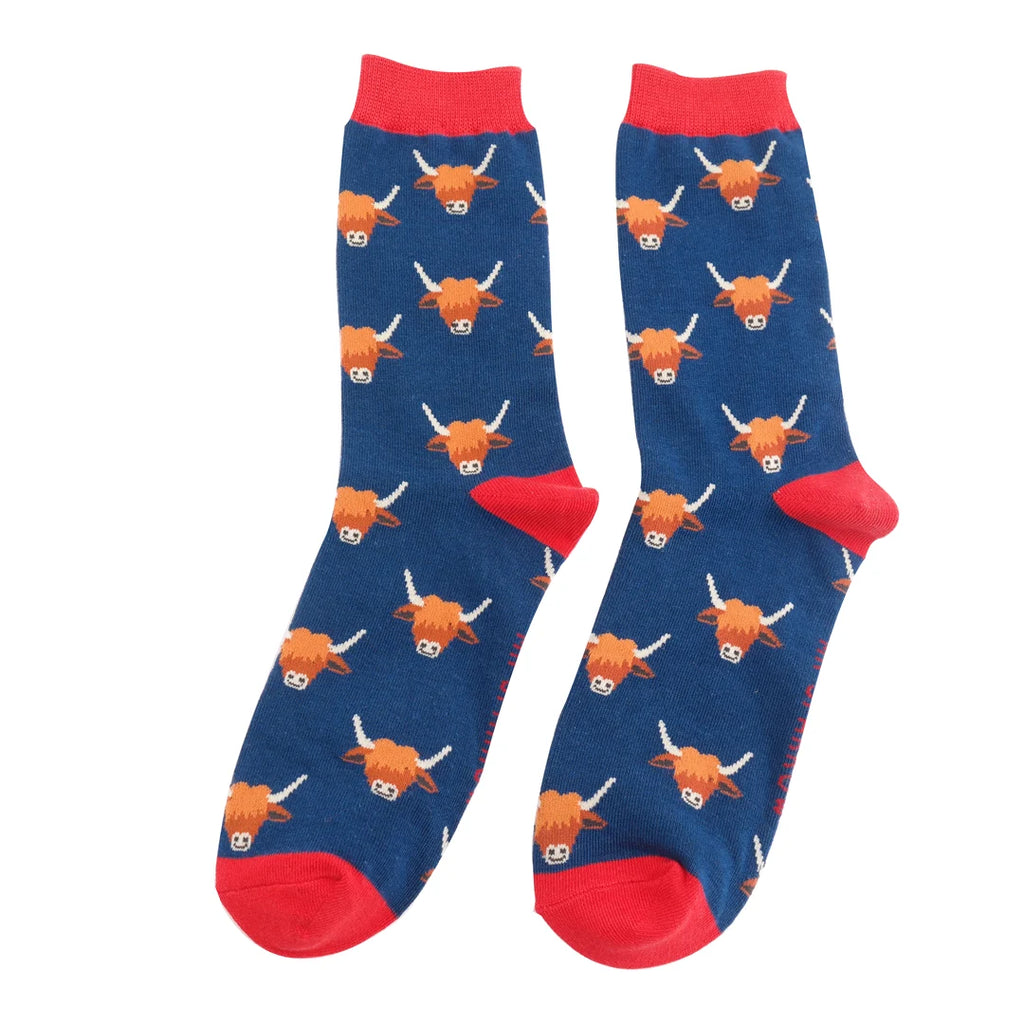 Pair of navy blue socks with a repeating pattern of Highland cow faces.  Red cuffs.