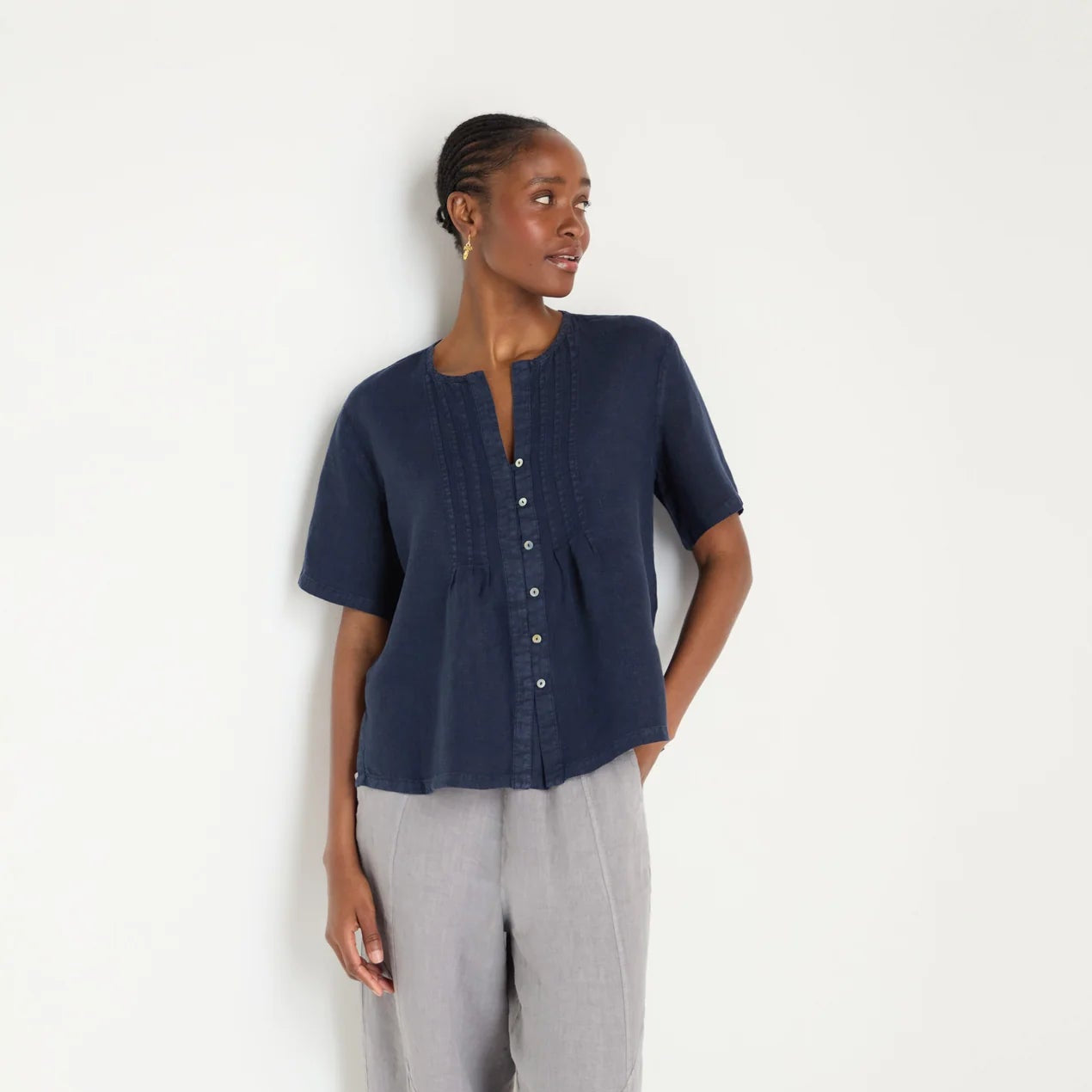 Woman wearing a navy blue top and gray pants on a white background