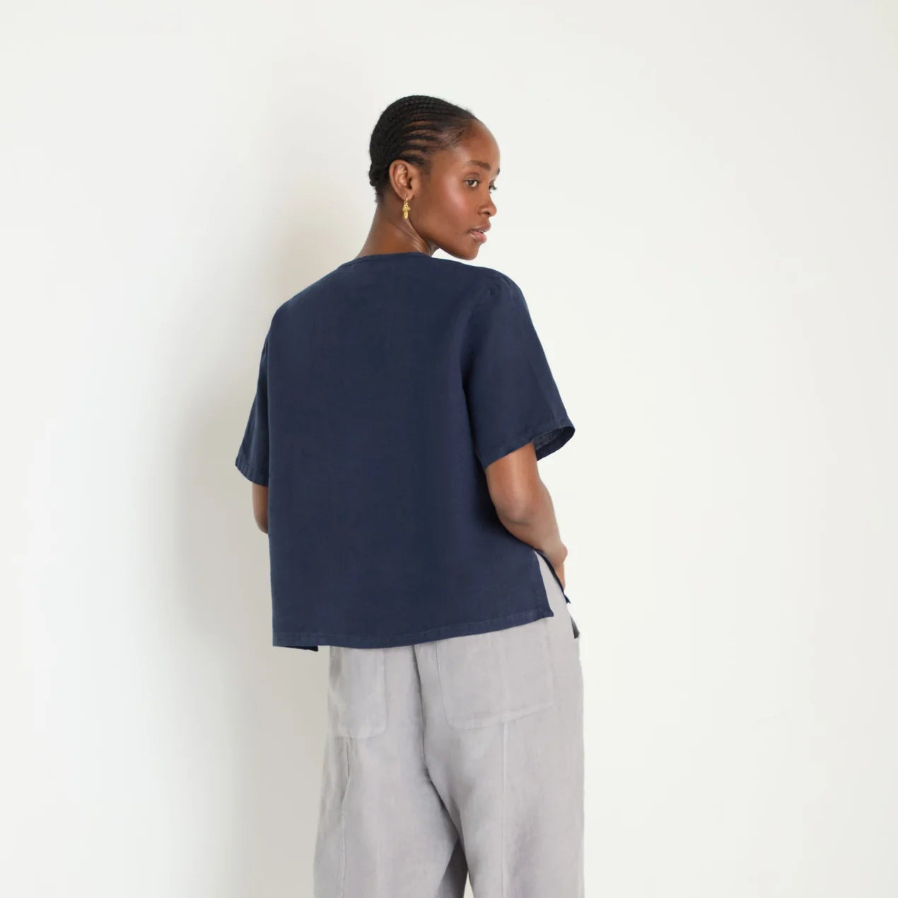 Person wearing a navy blue t-shirt and gray pants on a white background