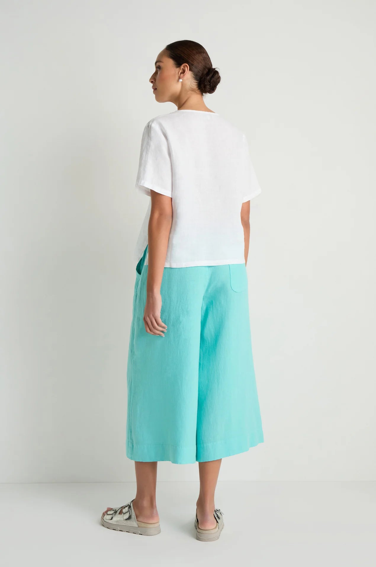 Woman wearing a white top and turquoise skirt on a plain background