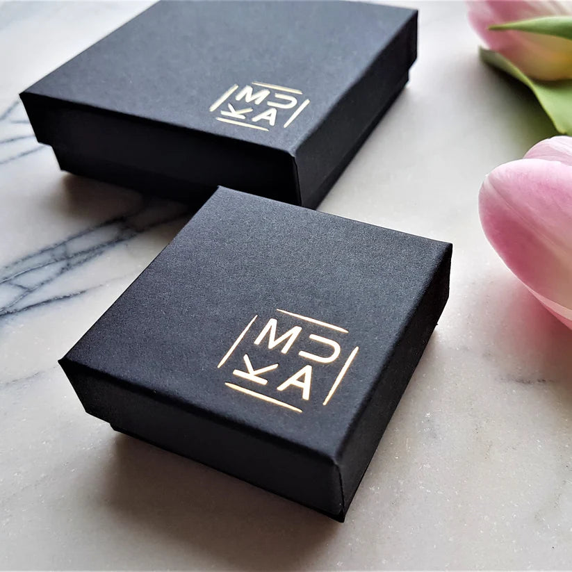 Two black square gift boxes with a gold "MJA" logo.