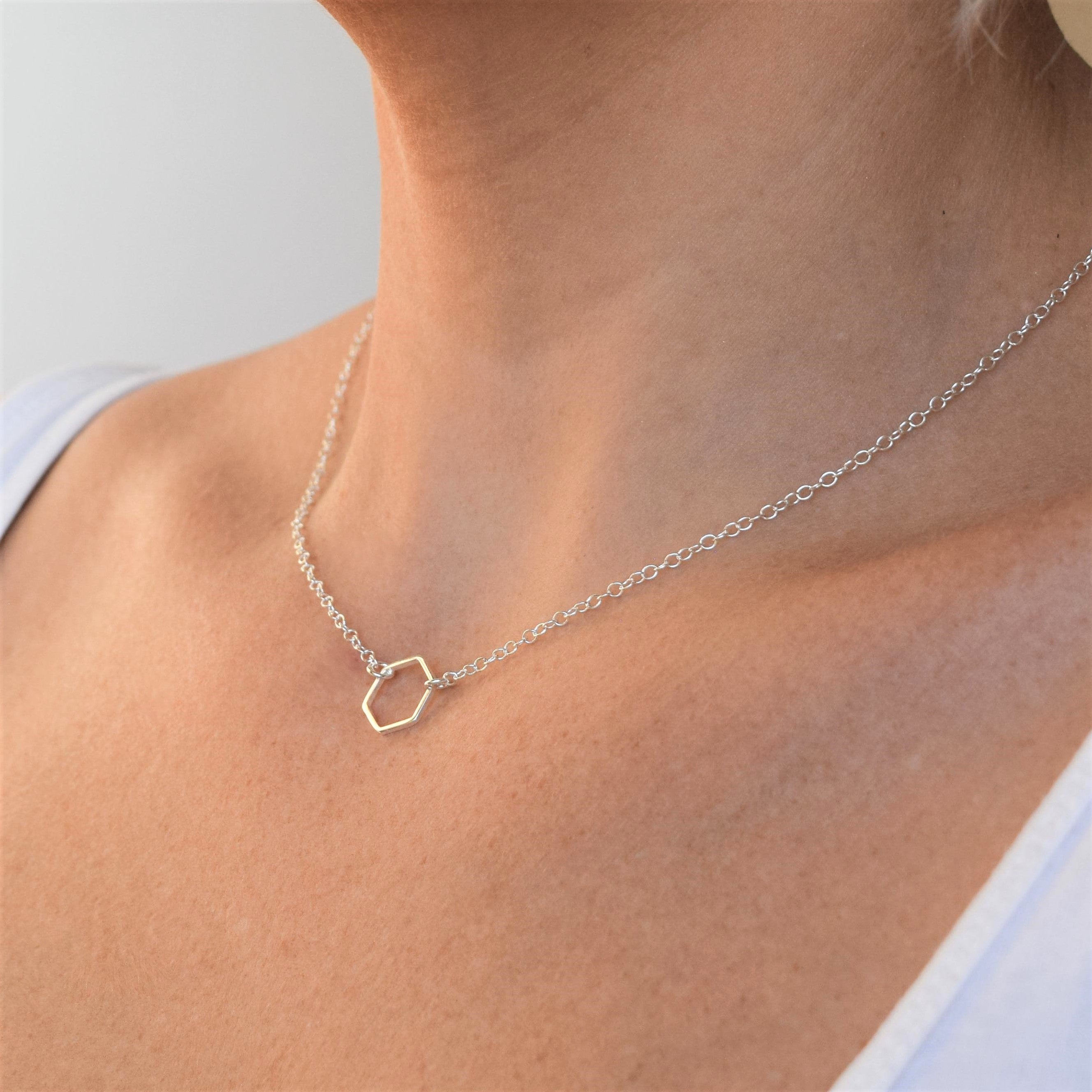 Silver chain necklace with a hexagonal pendant.