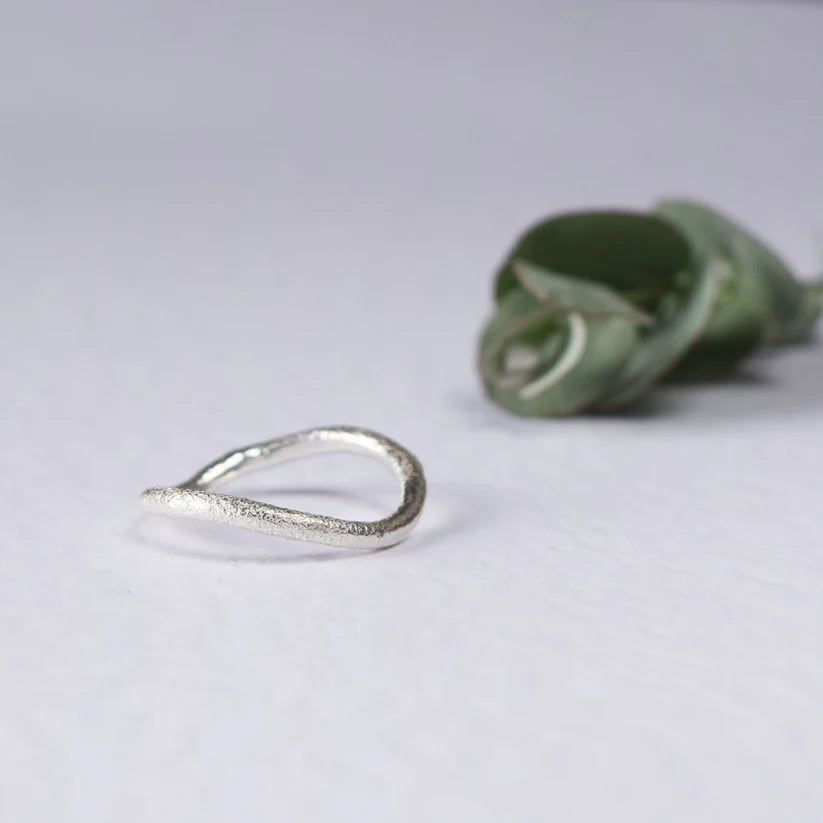 Silver ring with a textured, organic, asymmetrical, open-loop design.